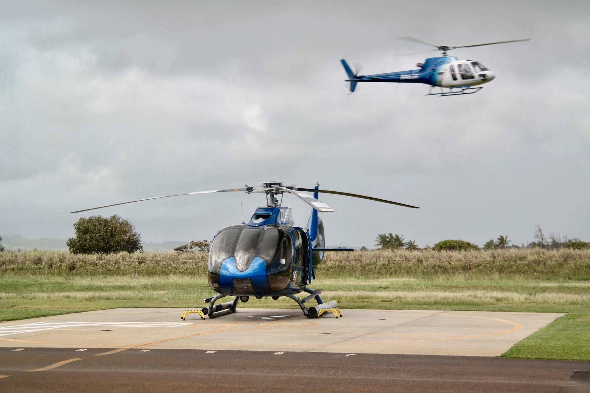 Helicopter on a helipad with another landing behind it