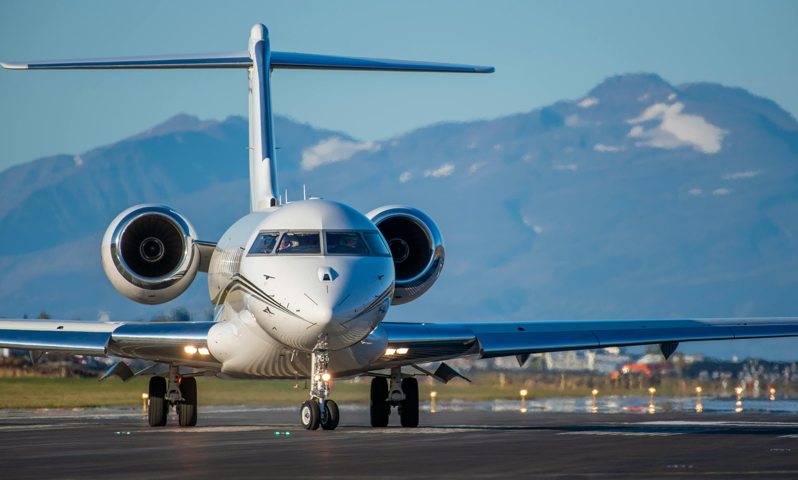 Private jet taxiing on a runway with mountains behind